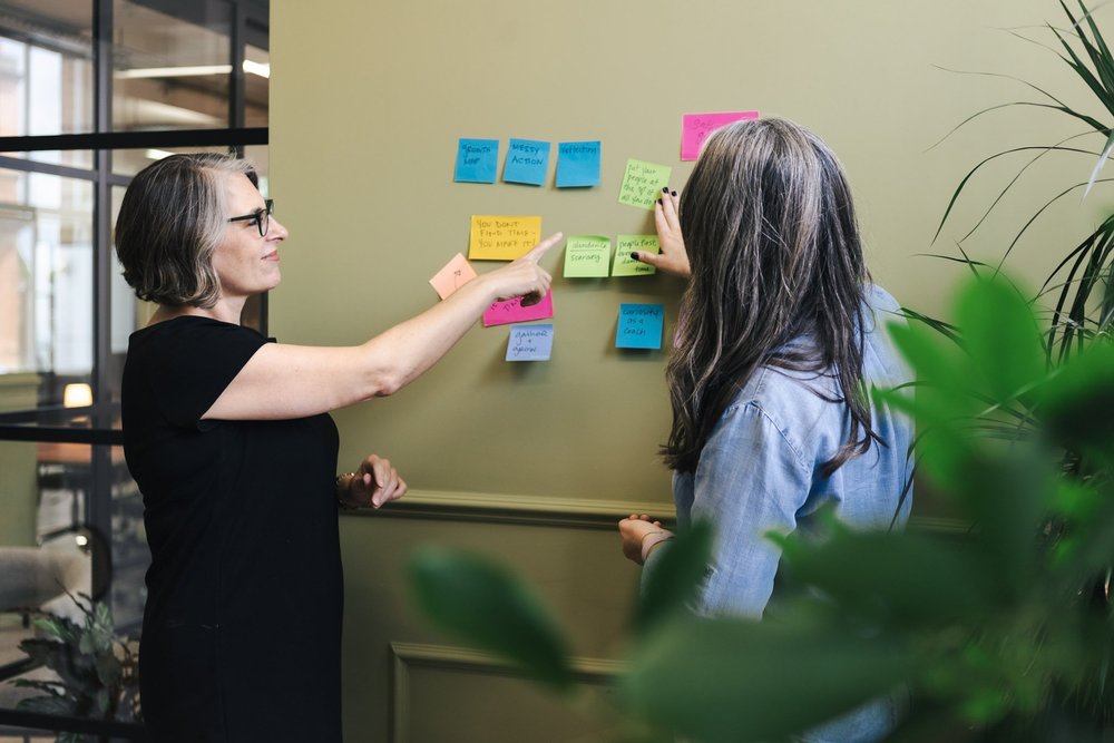 Two people exploring ideas together at a wall of workshop notes